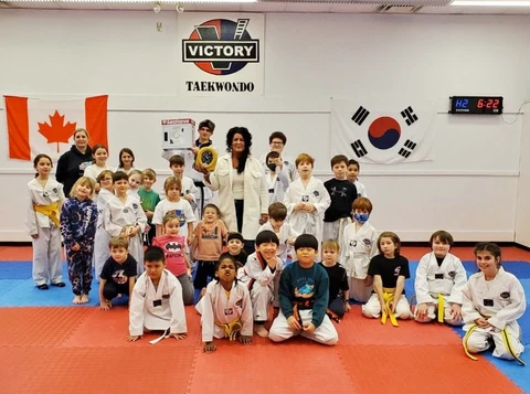 Victory Taekwondo students and adults gathered with the donated AED and wall cabinet.