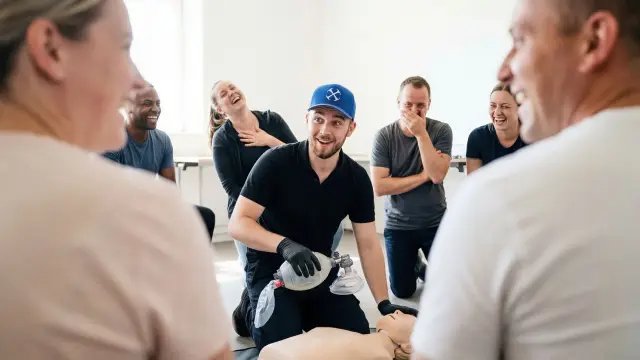 A first aid instructor and learners sharing a light moment during training